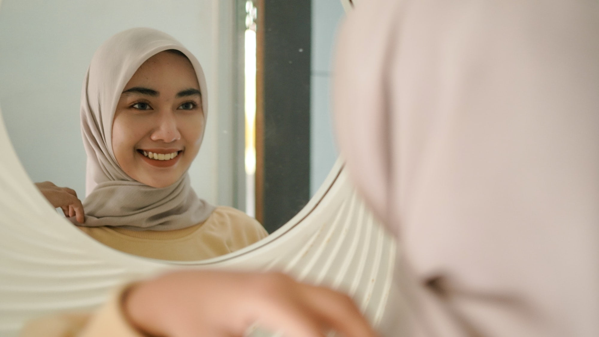 the beautiful young Muslim smiles sweetly in the mirror